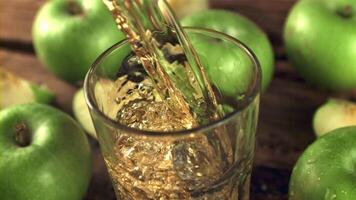 súper lento movimiento manzana jugo vierte dentro un vaso con aire burbujas en un de madera antecedentes. filmado en un alta velocidad cámara a 1000 fps. video