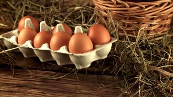 Super slow motion cardboard box with raw eggs falls on the table. On a wooden background. Filmed on a high-speed camera at 1000 fps. video