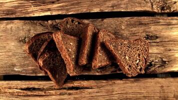 Super slow motion pieces of fresh bread fall on the table. On a wooden background. Filmed on a high-speed camera at 1000 fps.Top view. video