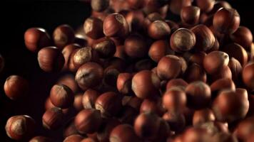 Super slow motion a bunch of hazelnuts takes off and falls. On a black background. Filmed on a high-speed camera at 1000 fps. video