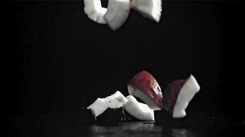 Pieces of coconut fall on the table. On a black background. Filmed on a high-speed camera at 1000 fps. High quality FullHD footage video