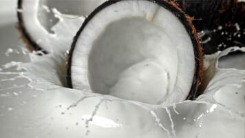 Half of the coconut falls into the milk with splashes. Filmed on a high-speed camera at 1000 fps. High quality FullHD footage video