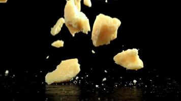 Parmesan Käse fallen auf ein schwarz Hintergrund. gefilmt auf ein schnelle Geschwindigkeit Kamera beim 1000 fps. hoch Qualität fullhd Aufnahmen video