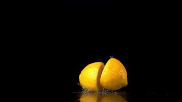 Super slow motion juicy lemon falls on the table and breaks into halves. On a black background.Filmed on a high-speed camera at 1000 fps. High quality FullHD footage video