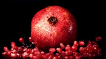 Super slow motion ripe pomegranate falls on the grain of the pomegranate. On a black background. Filmed on a high-speed camera at 1000 fps. High quality FullHD footage video