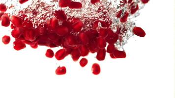 Super slow motion pomegranate grains fall under the water with air bubbles. On a white background.Filmed on a high-speed camera at 1000 fps. High quality FullHD footage video