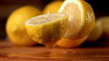 Super slow motion fresh lemon falls on the table and breaks into two halves. On a wooden background. Filmed on a high-speed camera at 1000 fps. High quality FullHD footage video