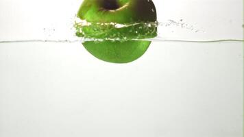 Super slow motion fresh juicy apple falls into the water with splashes. On a white background. Filmed on a high-speed camera at 1000 fps. High quality FullHD footage video