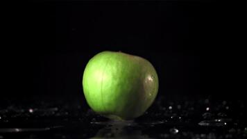 súper lento movimiento manzana caídas en el mesa y divisiones dentro dos mitades. en un negro antecedentes. filmado en un alta velocidad cámara a 1000 fps. alto calidad full HD imágenes video