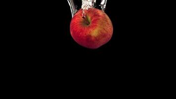 Super slow motion one red apple falls under the water with air bubbles. On a black background.Filmed on a high-speed camera at 1000 fps. High quality FullHD footage video