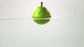 Super slow motion fresh pear falls under water. On a white background. Filmed on a high-speed camera at 1000 fps. High quality FullHD footage video