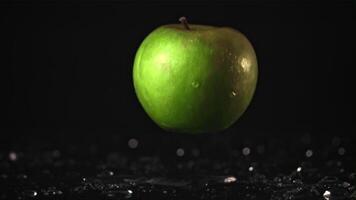 el súper lento movimiento de el manzana caídas en el mesa con agua. en un negro antecedentes. filmado en un alta velocidad cámara a 1000 fps. alto calidad full HD imágenes video