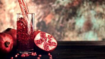 Super slow motion is a jet of pomegranate juice pouring into the glass on the table. Filmed on a high-speed camera at 1000 fps. On the rustic background. High quality FullHD footage video