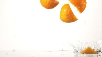 Super slow motion pieces of fresh lemon fall into the water with splashes. On a white background.Filmed on a high-speed camera at 1000 fps. High quality FullHD footage video