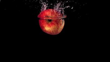 Super slow motion one red apple falls under the water with air bubbles. On a black background.Filmed on a high-speed camera at 1000 fps. High quality FullHD footage video