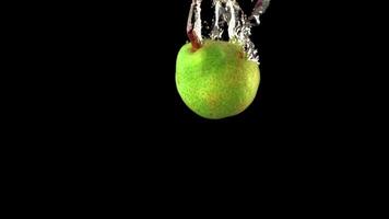 Super slow motion one green pear falls under the water with air bubbles. On a black background. Filmed on a high-speed camera at 1000 fps. High quality FullHD footage video