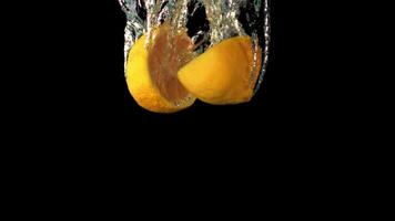 Super slow motion two halves of lemon fall under the water with air bubbles. On a black background.Filmed on a high-speed camera at 1000 fps. High quality FullHD footage video