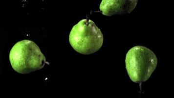 Super slow motion green pears fall on the water with splashes. On a black background.Filmed on a high-speed camera at 1000 fps. High quality FullHD footage video