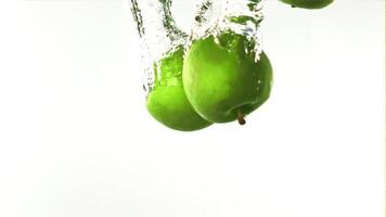 Super slow motion whole green apples fall under the water with air bubbles. On a white background. Filmed on a high-speed camera at 1000 fps. High quality FullHD footage video