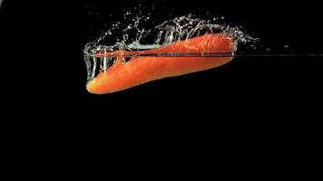 Super slow motion one ripe carrot falls into the water with splashes and air bubbles. On a black background. Filmed on a high-speed camera at 1000 fps.High quality FullHD footage video