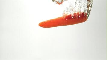 Super slow motion one carrot falls under the water with air bubbles. On a white background.Filmed on a high-speed camera at 1000 fps. High quality FullHD footage video