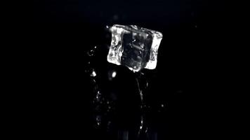 Super slow motion one ice cube falls on the table with splashes of water.Filmed on a high-speed camera at 1000 fps. On a black background. video