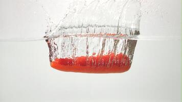 Super slow motion one carrot falls under the water with splashes and air bubbles. On a white background. Filmed on a high-speed camera at 1000 fps.High quality FullHD footage video