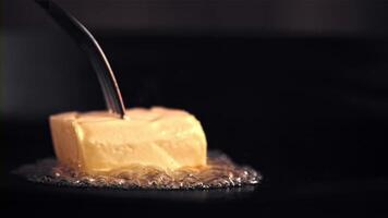 Super slow motion a piece of butter melts in a frying pan with air bubbles. On a black background.Filmed on a high-speed camera at 1000 fps. High quality FullHD footage video