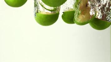 Super slow motion sliced apples fall under the water with air bubbles. On a white background.Filmed on a high-speed camera at 1000 fps. High quality FullHD footage video