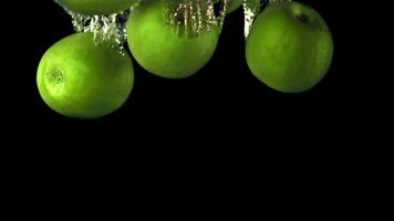 Super slow motion green apples fall under the water with air bubbles. On a black background. Filmed on a high-speed camera at 1000 fps. High quality FullHD footage video