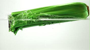 Super slow motion celery falls into the water with splashes. On a white background.Filmed on a high-speed camera at 1000 fps. High quality FullHD footage video