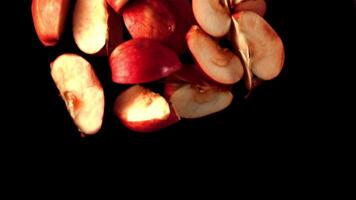 Super slow motion pieces of red apple fall into the water with splashes. On a black background. Filmed on a high-speed camera at 1000 fps. High quality FullHD footage video