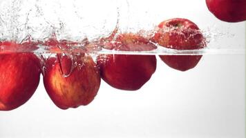 Super slow motion red apples fall into the water with splashes. On a white background.Filmed on a high-speed camera at 1000 fps. High quality FullHD footage video