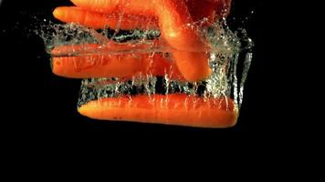 Super slow motion ripe carrot falls under water with air bubbles. On a black background. Filmed on a high-speed camera at 1000 fps. High quality FullHD footage video