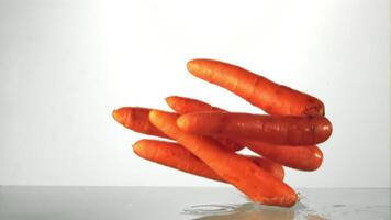 Super slow motion carrot falls into the water with splashes. On a white background.Filmed on a high-speed camera at 1000 fps. High quality FullHD footage video