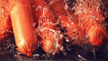 Super slow motion sausages fall on the water with splashes. On a black background. Filmed on a high-speed camera at 1000 fps. High quality FullHD footage video