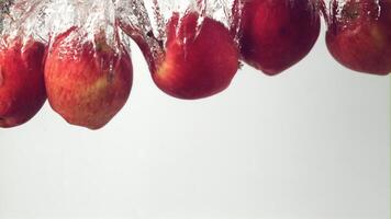 súper lento movimiento rojo manzanas otoño debajo el agua con aire burbujas en un blanco antecedentes. filmado en un alta velocidad cámara a 1000 fps. alto calidad full HD imágenes video