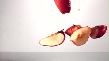 Super slow motion pieces of ripe apple fall into the water with splashes. On a white background.Filmed on a high-speed camera at 1000 fps. High quality FullHD footage video