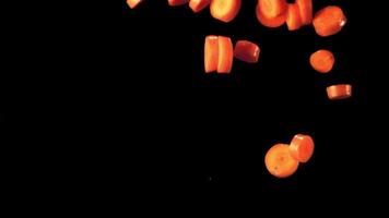 Super slow motion pieces of carrot fall into the water with splashes. On a black background. Filmed on a high-speed camera at 1000 fps. High quality FullHD footage video