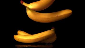 super langzaam beweging bananen vallen Aan de tafel. Aan een zwart achtergrond. gefilmd Aan een hoge snelheid camera Bij 1000 fps. video