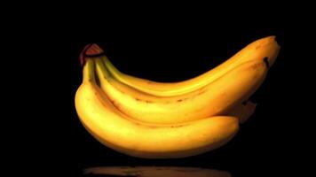 Super slow motion a bunch of bananas on a black background falls on the table. Filmed on a high-speed camera at 1000 fps. High quality FullHD footage video