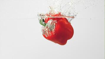 Super slow motion one red bell pepper falls under the water on a white background.Filmed on a high-speed camera at 1000 fps. High quality FullHD footage video