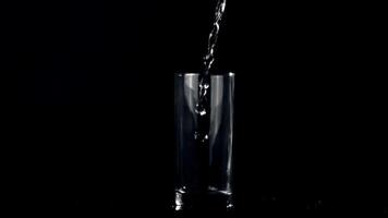 Super slow motion jet of water pours into the glass on the table. On a black background. Filmed on a high-speed camera at 1000 fps. video