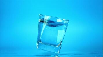 Super slow motion glass with water falls on the table with splashes.Filmed at 1000 fps. On a blue background. video