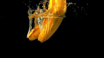 Super slow motion fresh bananas fall into the water with splashes. On a black background.Filmed at 1000 fps. video