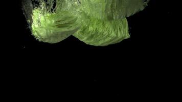 Super slow motion chunks of fresh cabbage fall under the water with air bubbles. Filmed on a high-speed camera at 1000 fps. On a black background. video