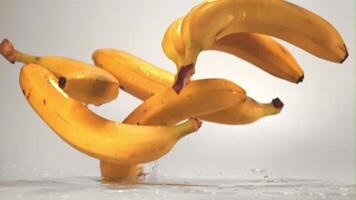 Super schleppend Bewegung Bananen auf ein Weiß Hintergrund fallen auf ein Tabelle mit Spritzer.gefilmt auf ein schnelle Geschwindigkeit Kamera beim 1000 fps. hoch Qualität fullhd Aufnahmen video