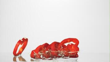 Super slow motion sliced red pepper falls on the water with splashes. On a white background.Filmed on a high-speed camera at 1000 fps. video