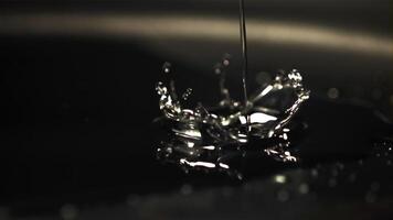 Super slow motion jet oil falls on the pan with splashes. On a black background. Filmed on a high-speed camera at 1000 fps. video