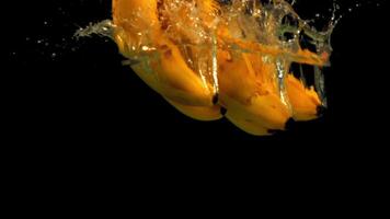 Super slow motion fresh bananas fall into the water with splashes. On a black background.Filmed at 1000 fps. video